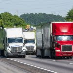 Three large semi-trucks crowd an Interstate Highway